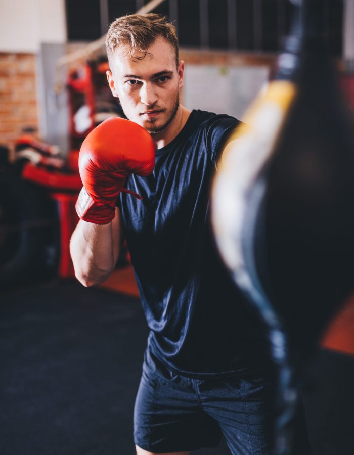 Boxer do boxing training with punchbag on a gym